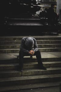 A person sitting alone in low light, looking down