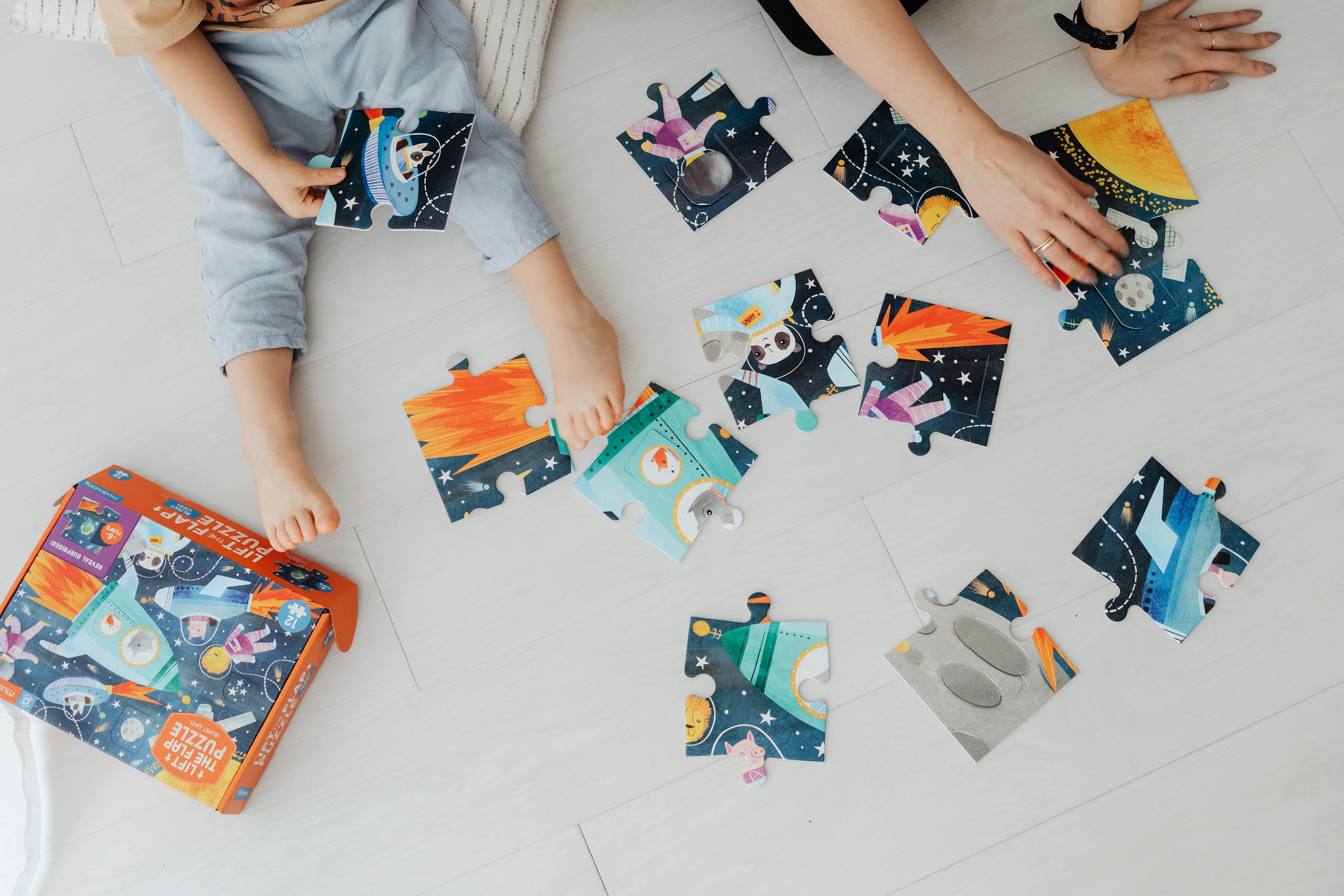 Children solving a colourful jigsaw puzzle together, seen from above