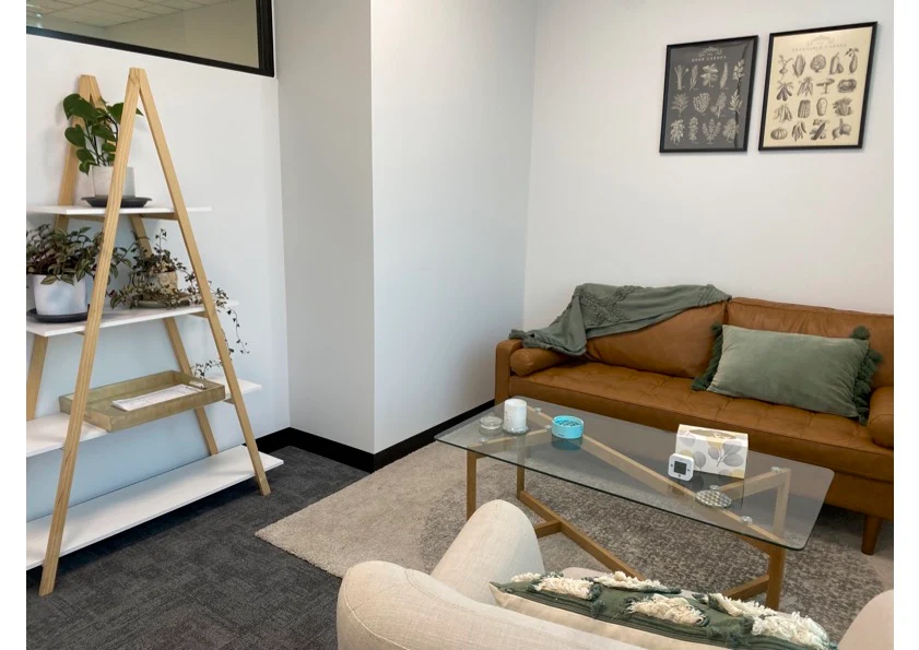 A consulting room for hire with a leather sofa, armchair and plants at Your Mind Matters in Notting Hill