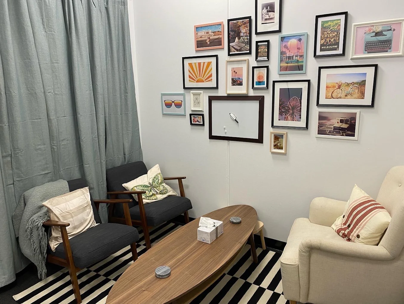 A consulting room for hire with mid-century armchairs and a gallery wall of framed prints