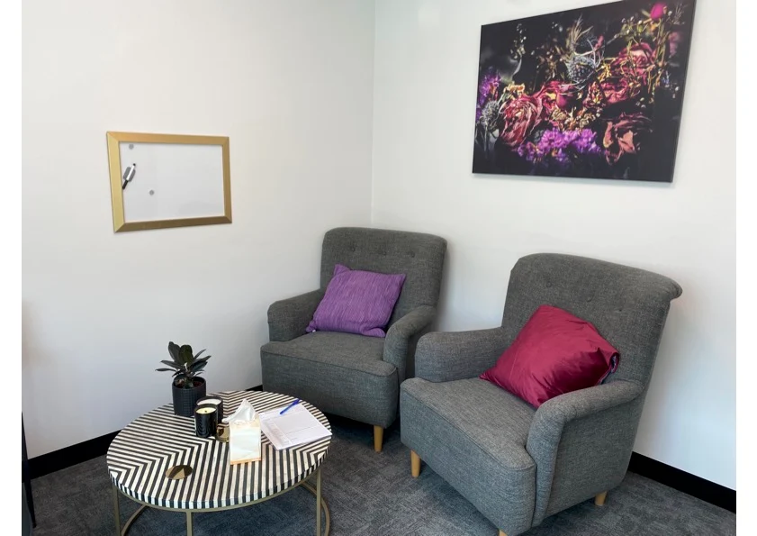 A consulting room for hire with two grey armchairs facing each other and a round coffee table
