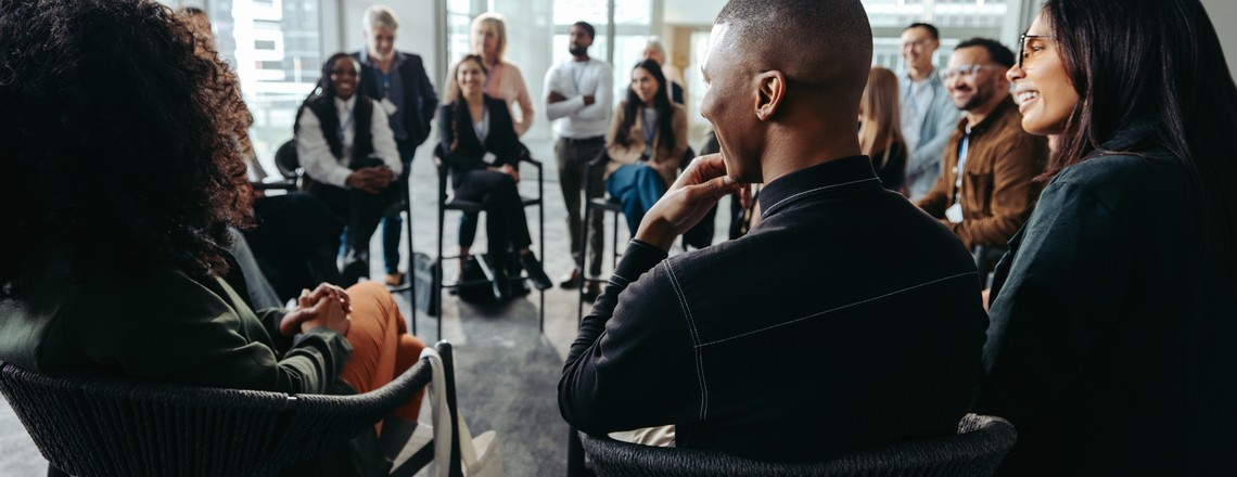 Colleagues seated in a circle at a workplace session, listening and talking