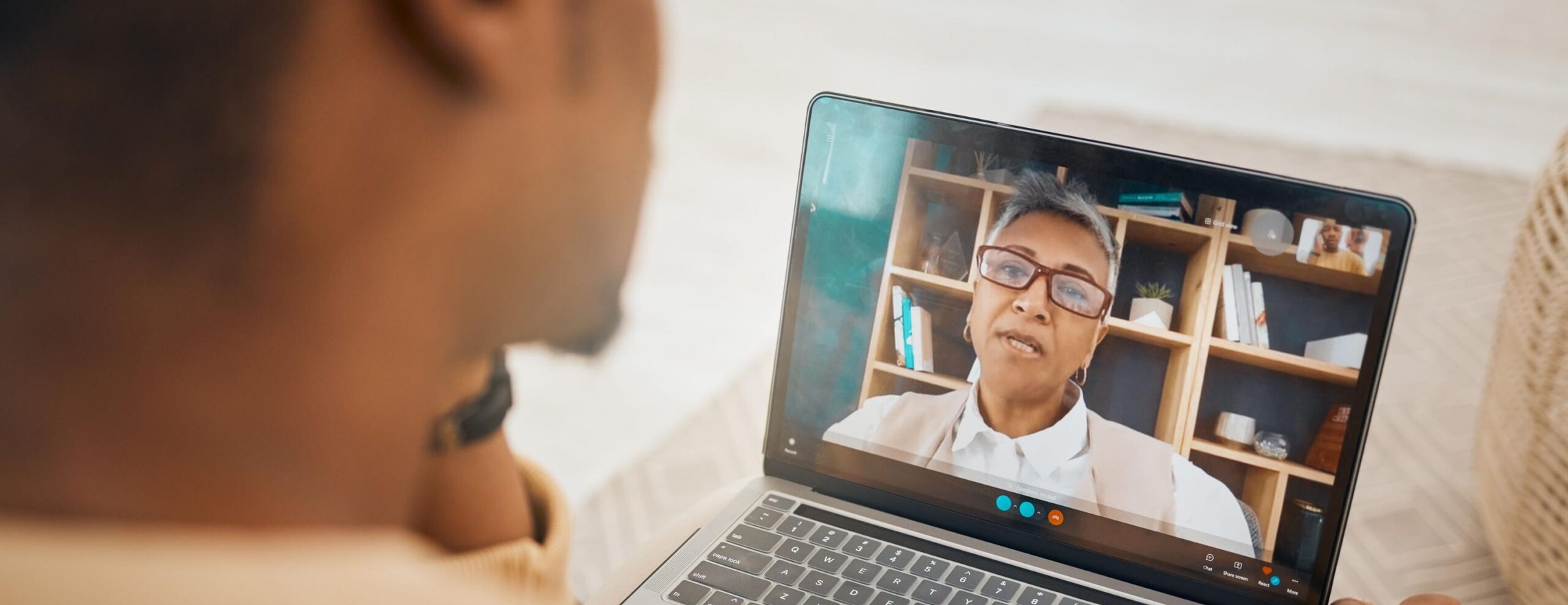 A man at home looking at a laptop screen where a psychologist is speaking during a video session