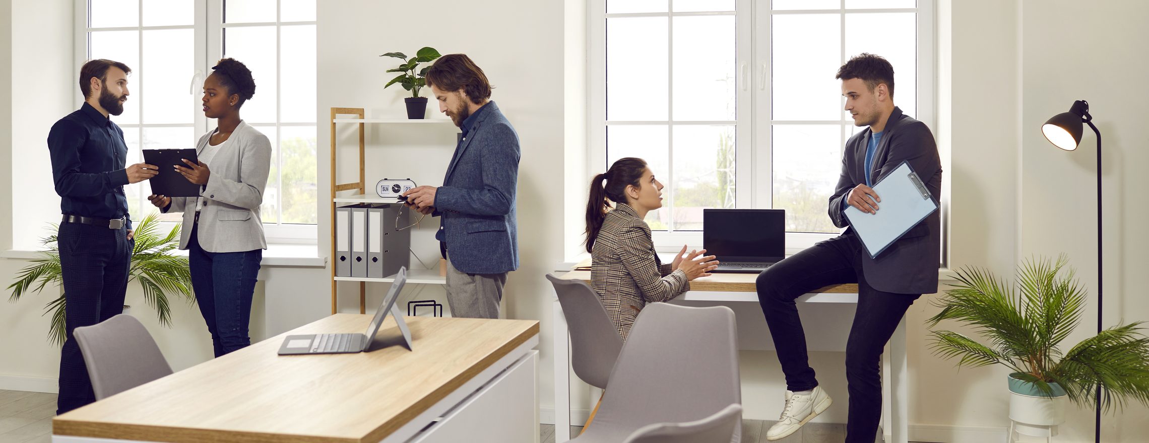 Colleagues talking in pairs across a bright open-plan office