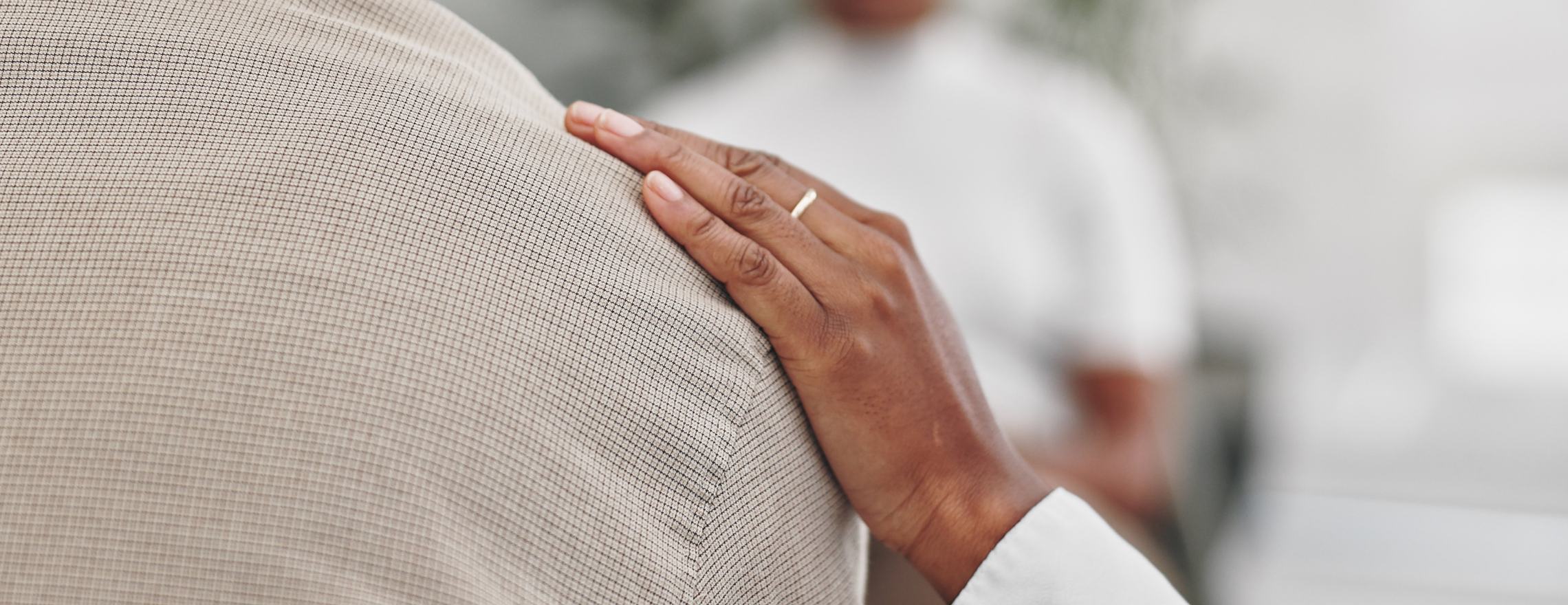 A hand resting on a person’s shoulder during a therapy session