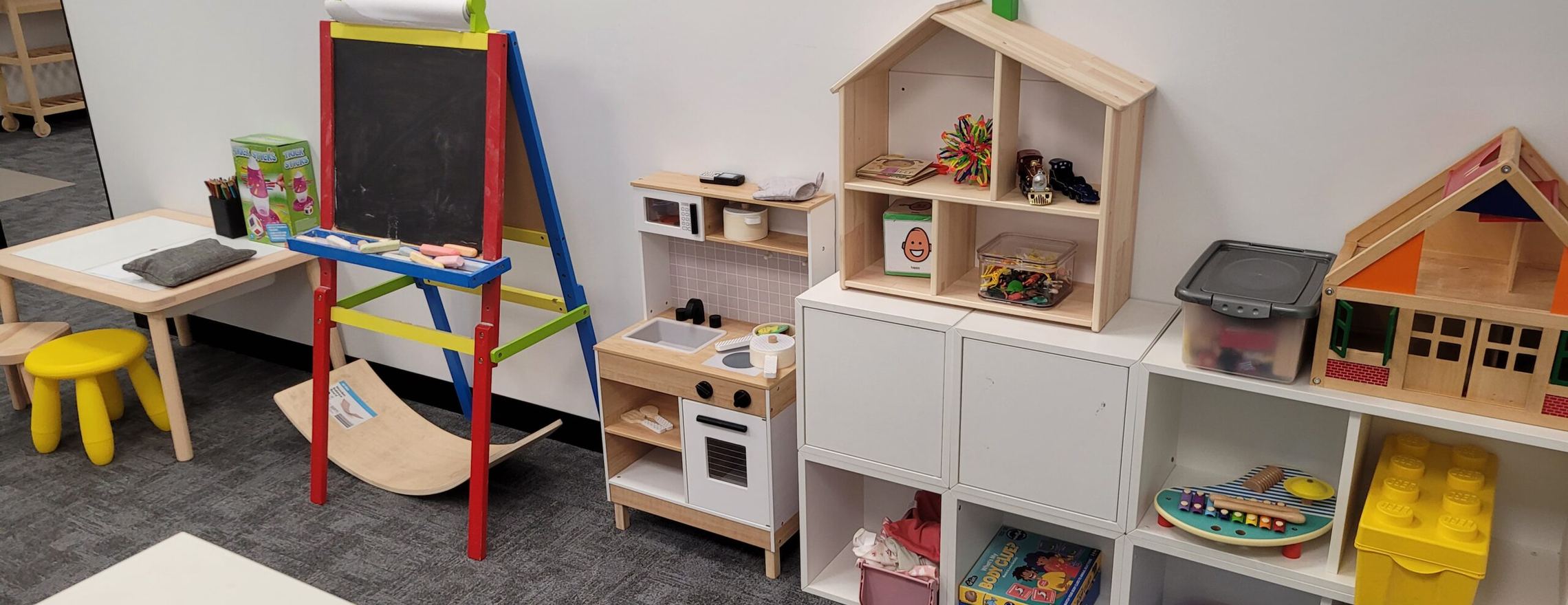 The children’s therapy room at Your Mind Matters, with an easel, a play kitchen and shelves of toys