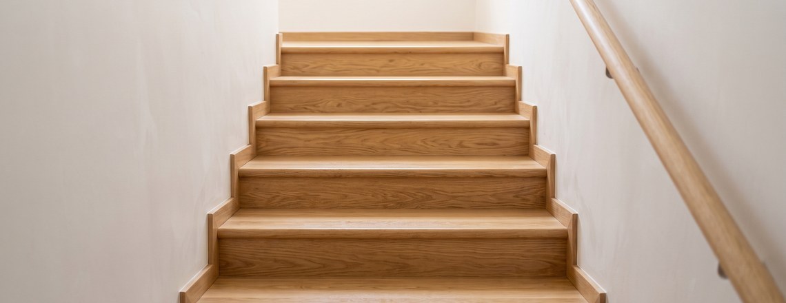 A plain timber staircase seen from below, lit by soft daylight from above